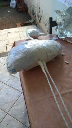 an animal laying on top of a table covered in plastic wrap next to a brick wall