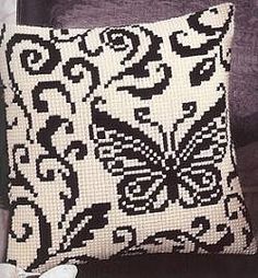 a black and white pillow sitting on top of a wooden table next to a flower