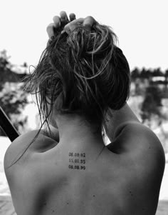 the back of a woman's neck with numbers tattooed on her upper and lower back