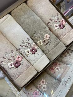 four towels in a box with flowers on the front and back, sitting on top of each other