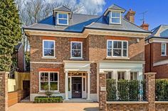 a large brick house with lots of windows and bushes in front of the entrance to it