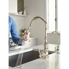 a woman is washing her hands under the kitchen faucet with water running from it