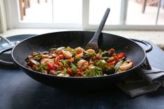 a skillet filled with shrimp, broccoli and other vegetables on top of a table