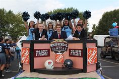 a group of young people standing on top of a float in a parking lot with cheerleaders