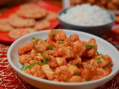 a white bowl filled with fried food next to other foods on a red table cloth