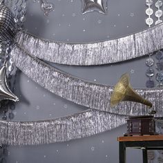 a party decoration with silver streamers, balloons and a megaphone on a table