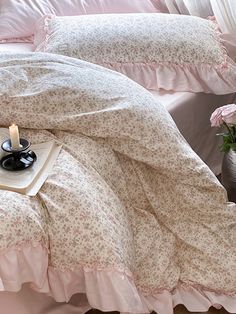 a bed with pink comforter and two candles on the end table next to it