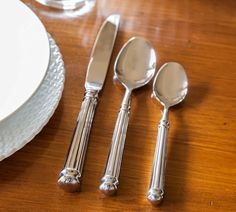 four silverware on a wooden table with white plates