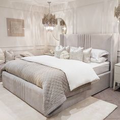 a bedroom with a large bed and chandelier hanging from the ceiling