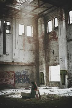 a person sitting on a bench in an abandoned building