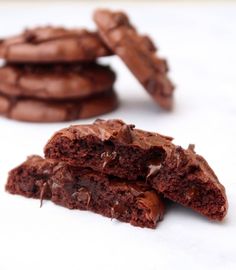 some chocolate cookies are stacked on top of each other and one is broken in half