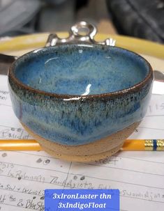 a blue and brown bowl sitting on top of a table next to a pencil holder