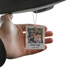 a hand holding a photo ornament that says drive safe