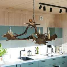 a wooden chandelier hanging from the ceiling in a kitchen with blue cabinets and white counter tops