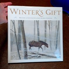 a person holding up a book about the winter's gift with a horse running through it