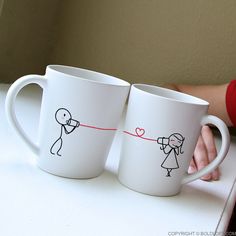 two coffee mugs with stick figures drawn on them