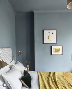 a bedroom with blue walls and white bedding, yellow blanket on the headboard