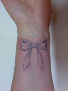 a wrist tattoo with a bow on it