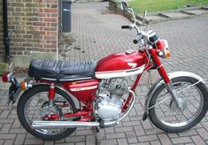 a red motorcycle parked on top of a brick sidewalk