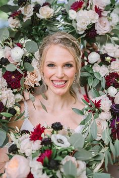 a woman holding a bunch of flowers in front of her face and smiling at the camera