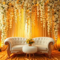 a white couch sitting in front of a yellow curtain with flowers hanging from the ceiling