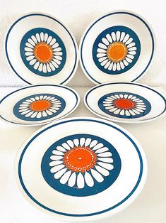 four white and blue plates with orange centers