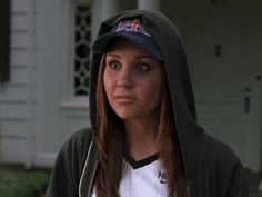 a girl in a hoodie and cap looking at the camera with an intense look on her face