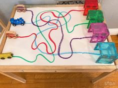 a child's play table with toy cars and trucks on the white board in front of it