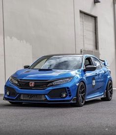 a blue car parked in front of a building with the words honda written on it