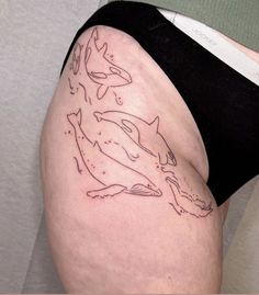 a woman's thigh with an orca whale tattoo on her left side, and two dolphins in the background