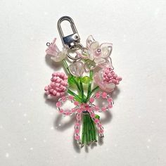 a pink and white flower keychain is shown on a white surface with tiny beads