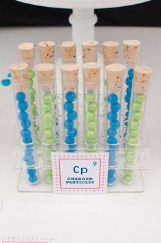 several tubes filled with green and blue beads in front of a white cake topper