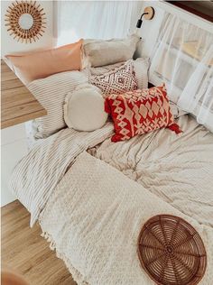 a bed with pillows and blankets on top of it next to a wall mounted fan