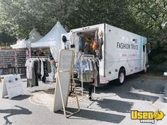 a white truck parked in front of a tent with clothes on it's sides