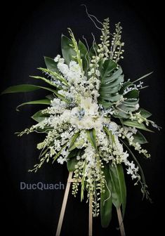 a bouquet of white flowers and greenery on a black background