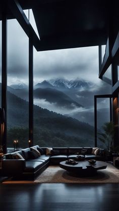 a living room filled with lots of furniture under a window covered in foggy mountains