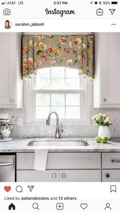 a kitchen window with flowers on the valance, and a sink in front of it