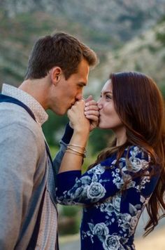 a man and woman standing next to each other with their hands on their mouths together