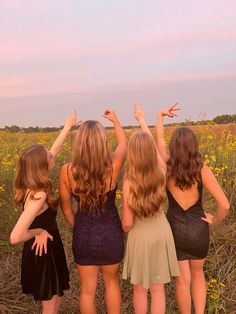 four girls standing in a field with their arms up