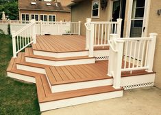 a wooden deck with white railings next to a house