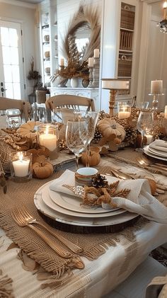 a dining room table is set with place settings, candles and napkins on it