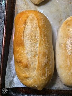 two loaves of bread sitting on top of a baking pan next to each other