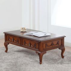 a wooden coffee table with drawers on top and a book sitting on it's side