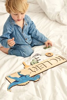 a little boy sitting on top of a bed next to a wooden sign