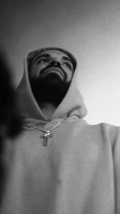 black and white photograph of a man wearing a hoodie looking up at the sky