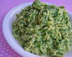 a white bowl filled with pasta and broccoli on top of a pink table cloth