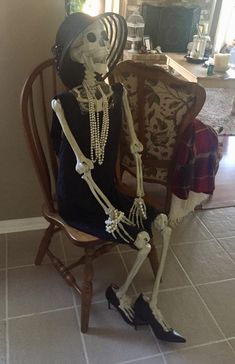 a skeleton sitting on top of a wooden chair