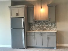 an empty kitchen with refrigerator and cabinets in it