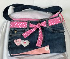 a handbag with pink and white polka dots on the front, blue denim jeans