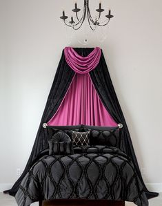 a black and pink bed with a chandelier hanging from it's side